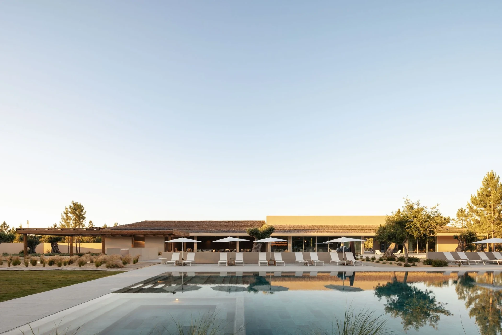 The main pool at Estates Spatia at golden hour, clubhouse behind.